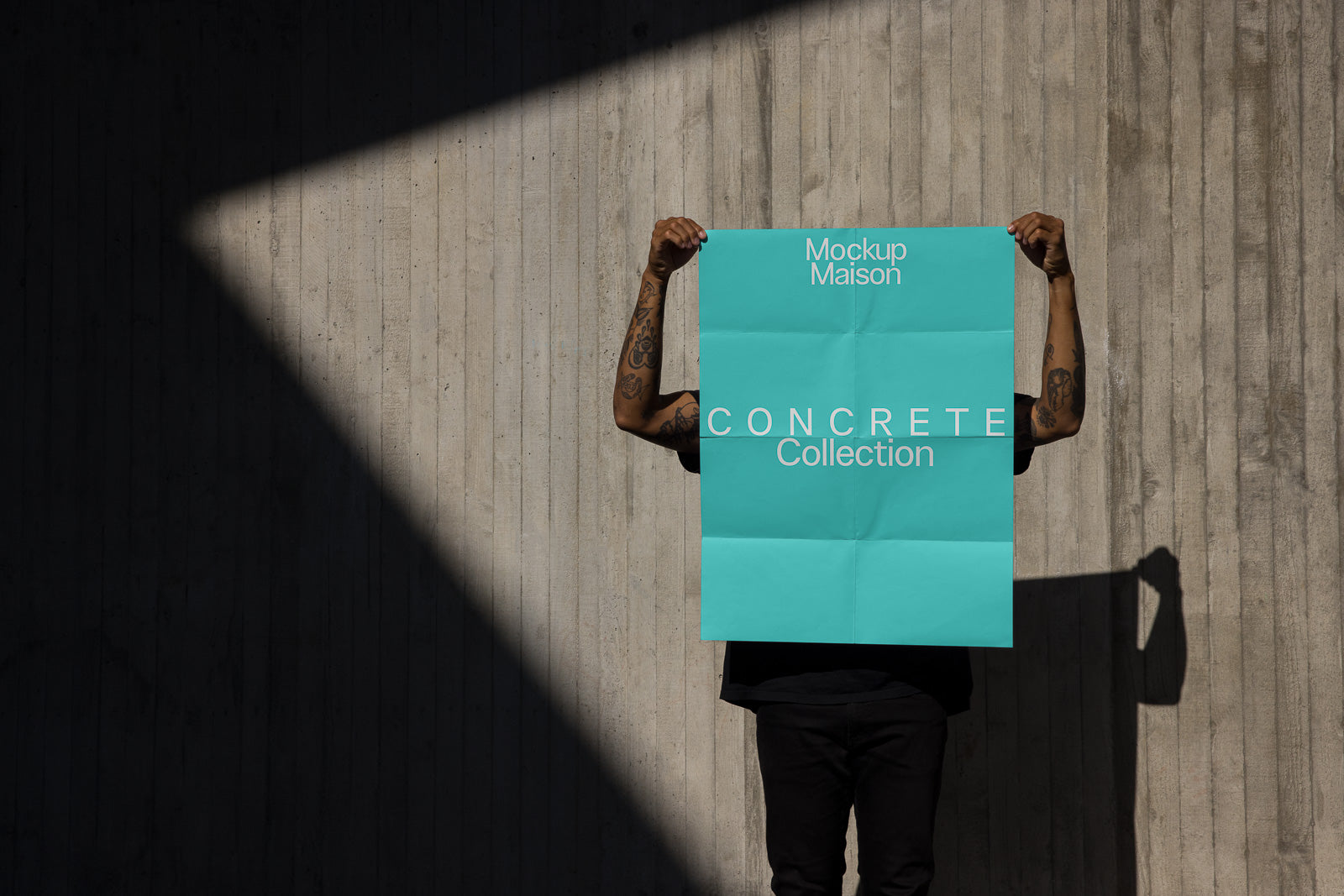 PSD mockup of a person holding a large turquoise poster with "Mockup Maison Concrete Collection" text, standing against a textured concrete wall with dramatic lighting.