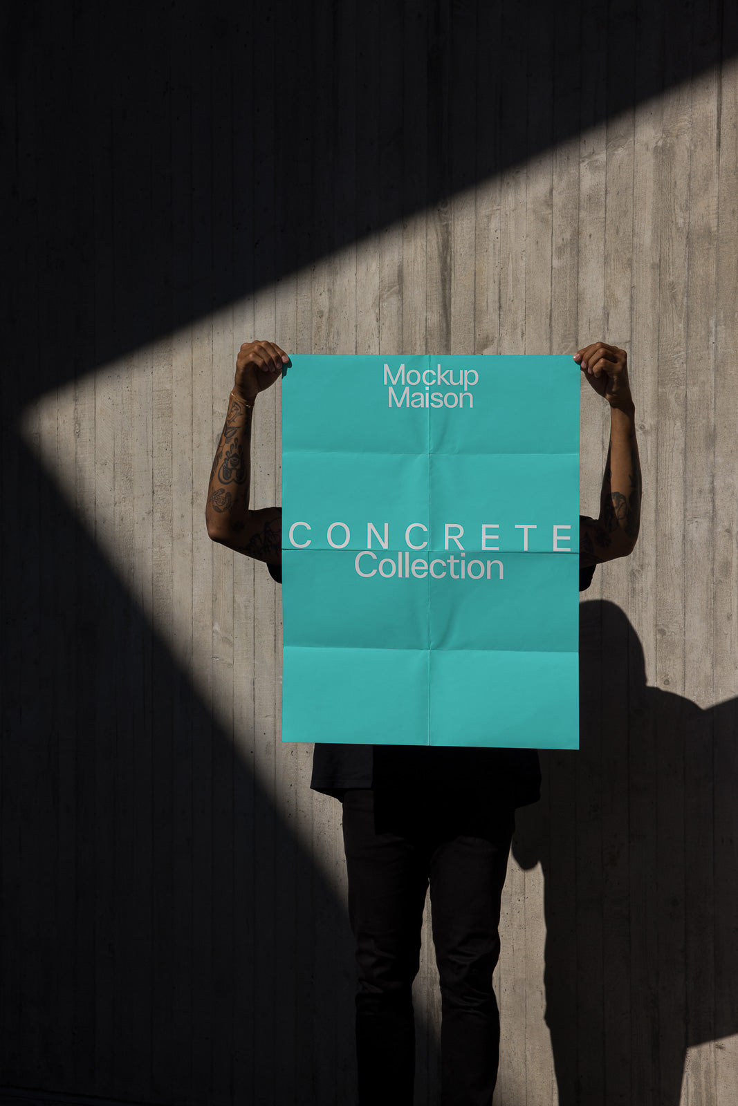 PSD mockup of a person holding a blue poster with "Mockup Maison CONCRETE Collection" text against a textured concrete wall backdrop.