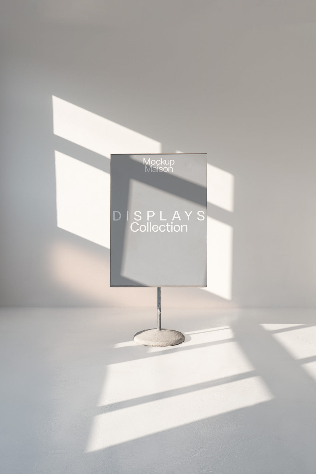 PSD mockup of a freestanding poster display in a minimalist setting with natural light casting geometric shadows on the floor.