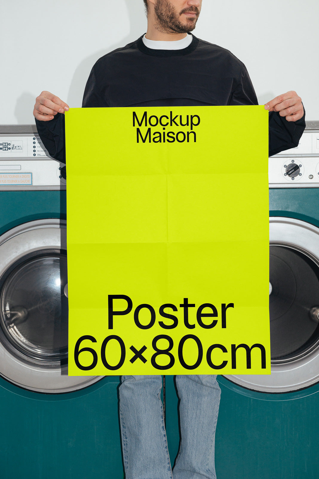 PSD mockup of a person holding a large yellow 60x80 cm poster in front of laundromat machines, with "Mockup Maison" text.