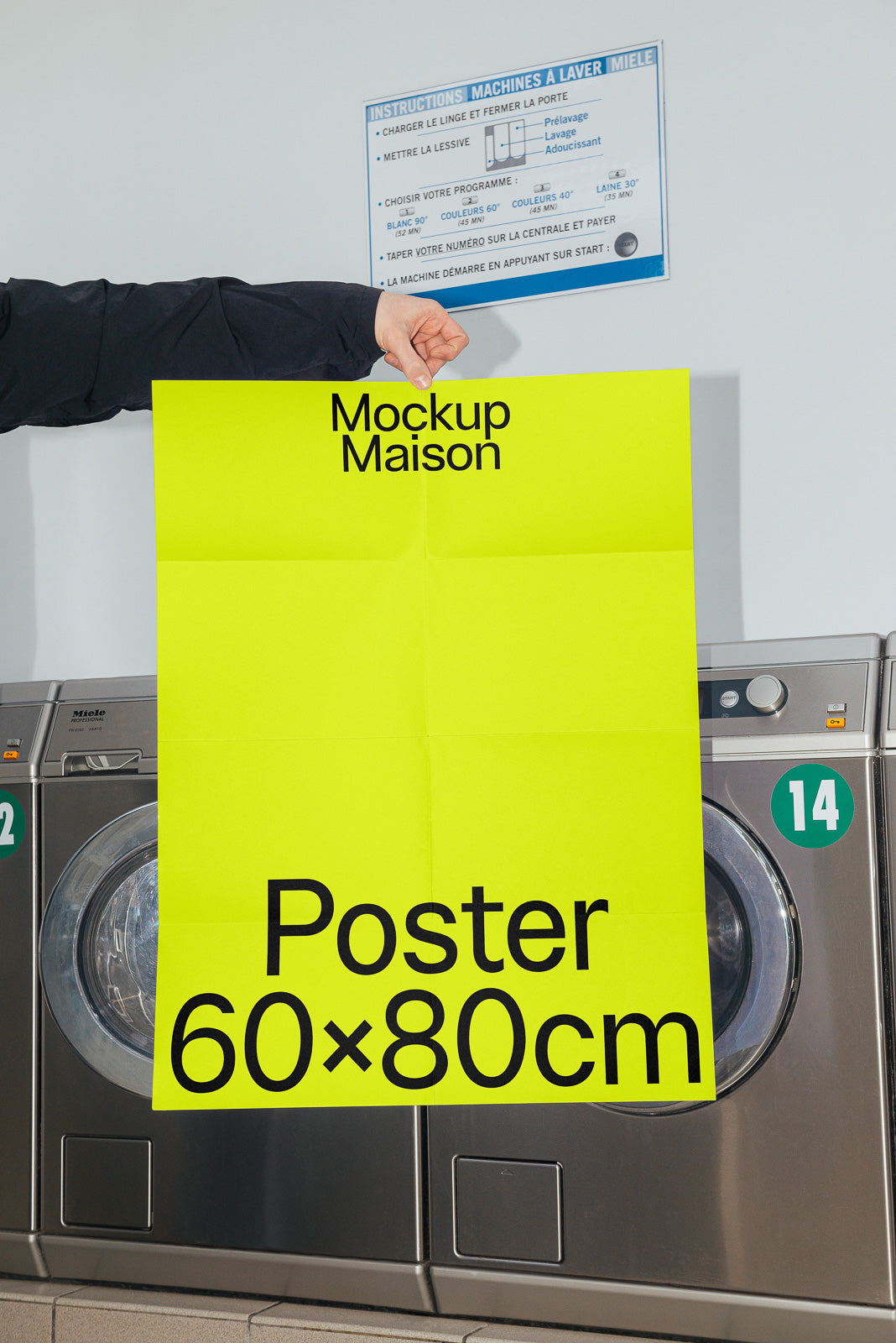 PSD mockup of a bright yellow 60x80cm poster held in front of industrial washing machines in a laundry setting.