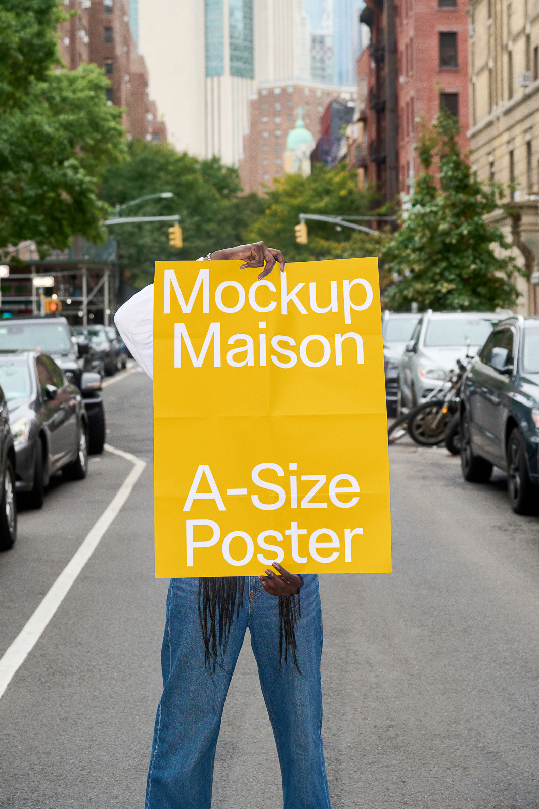 PSD mockup of a person holding a large yellow A-size poster on a city street, with text "Mockup Maison A-Size Poster" in bold white letters.