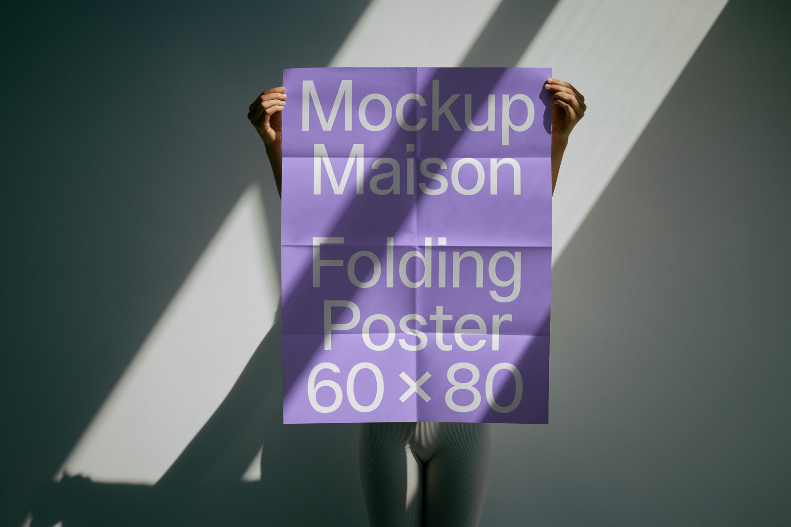 PSD mockup of a person holding a large purple folding poster with text "Mockup Maison Folding Poster 60 x 80" against a wall lit by sunlight.