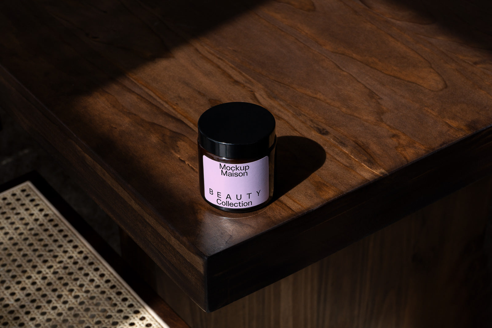 PSD mockup of a cosmetic jar labeled "Mockup Maison Beauty Collection," set on a wooden table in natural light with shadows.