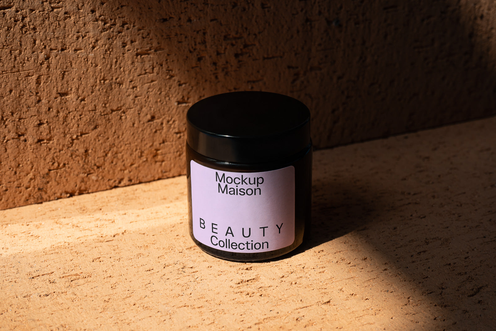 PSD mockup of a beauty collection jar labeled "Mockup Maison." The jar sits on a textured surface, illuminated by natural light.