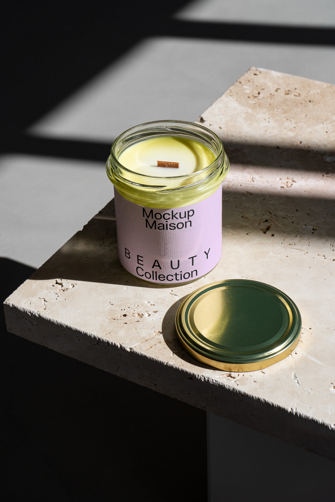 PSD mockup of a candle in a glass jar with a light purple label, placed on a stone surface in natural light, with the lid beside it.
