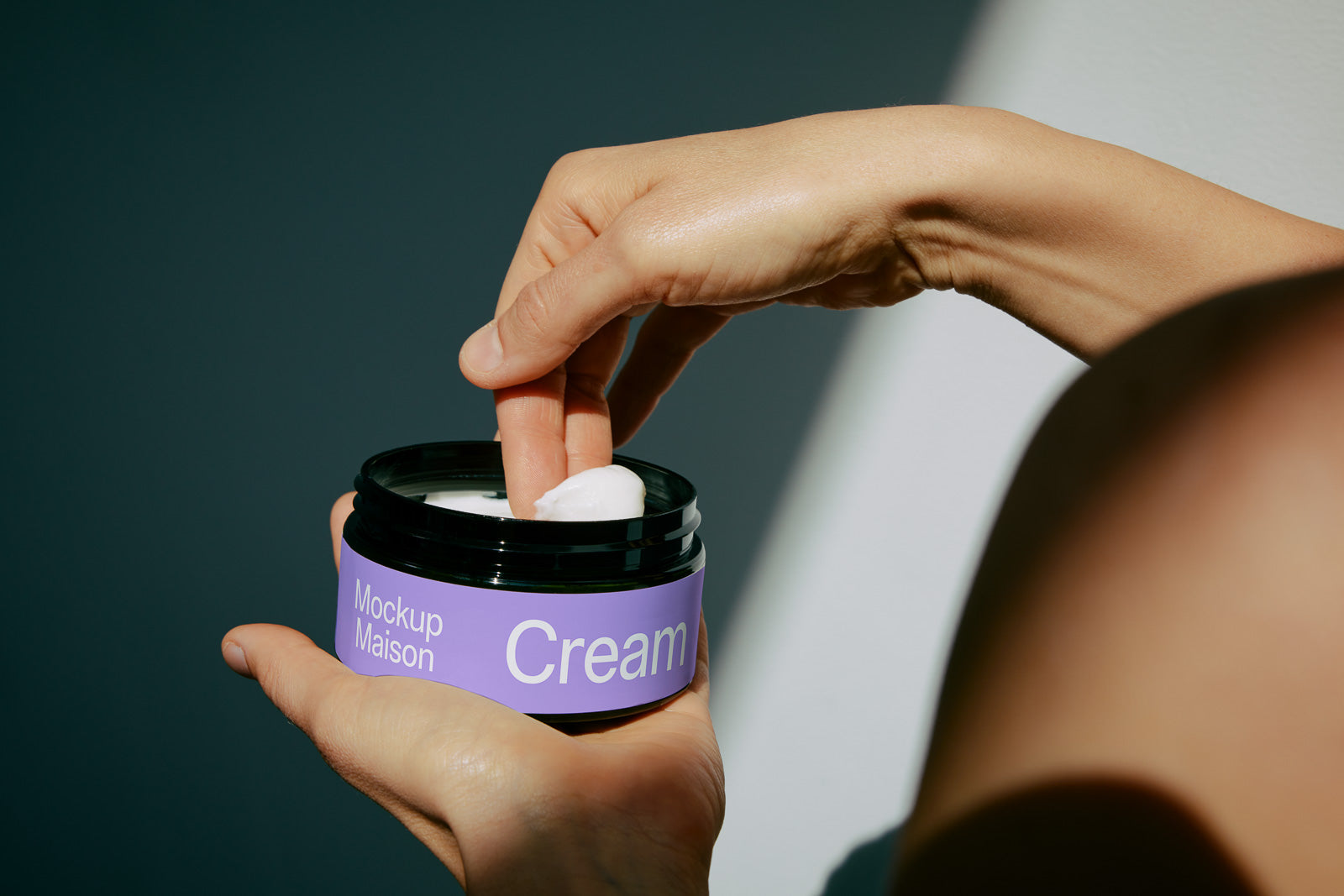 PSD mockup of a person holding a jar labeled "Mockup Maison Cream," with fingers dipping into the cream, highlighting texture and packaging.
