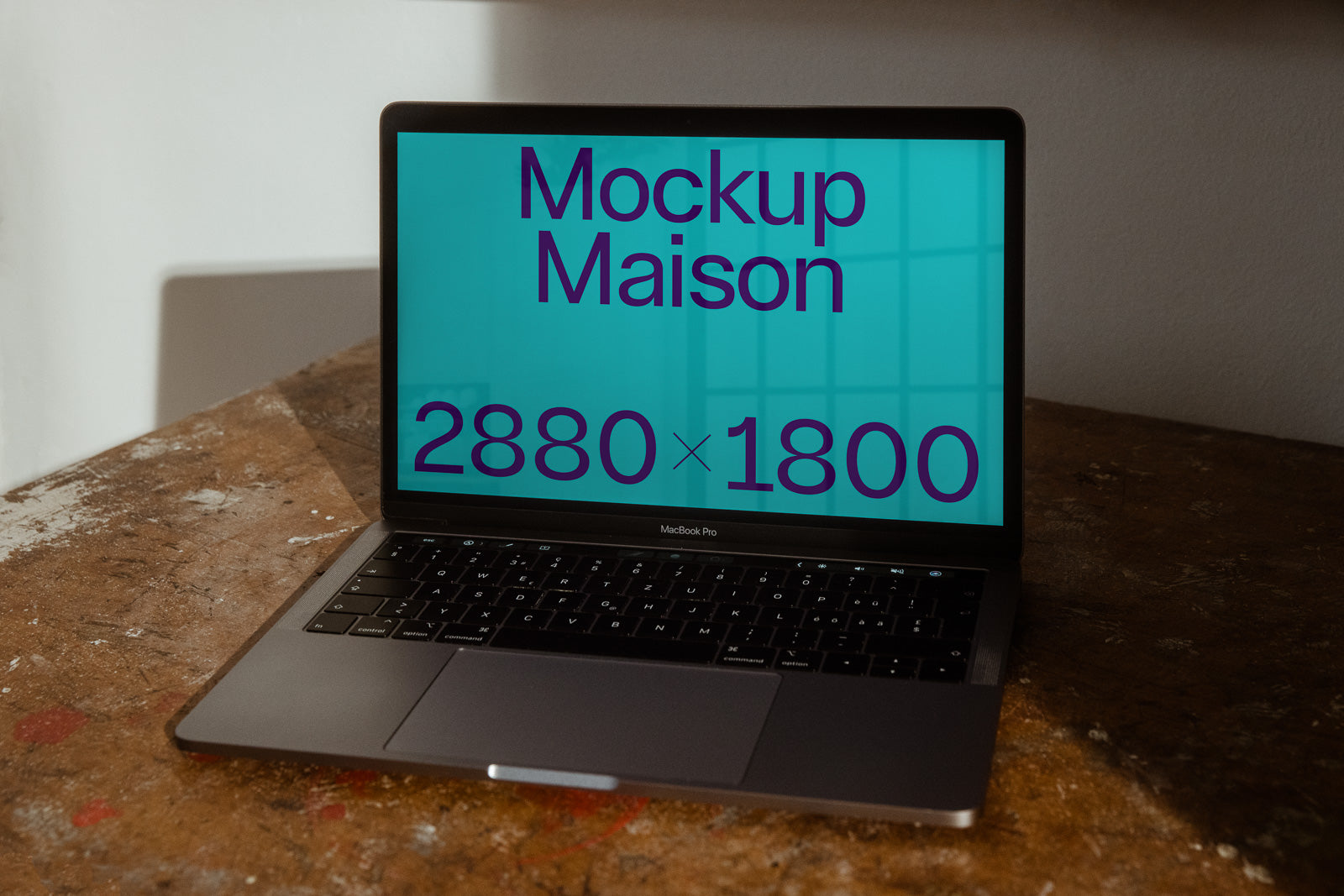 PSD mockup of a MacBook Pro on a wooden desk, displaying text "Mockup Maison 2880 x 1800" on a teal background.