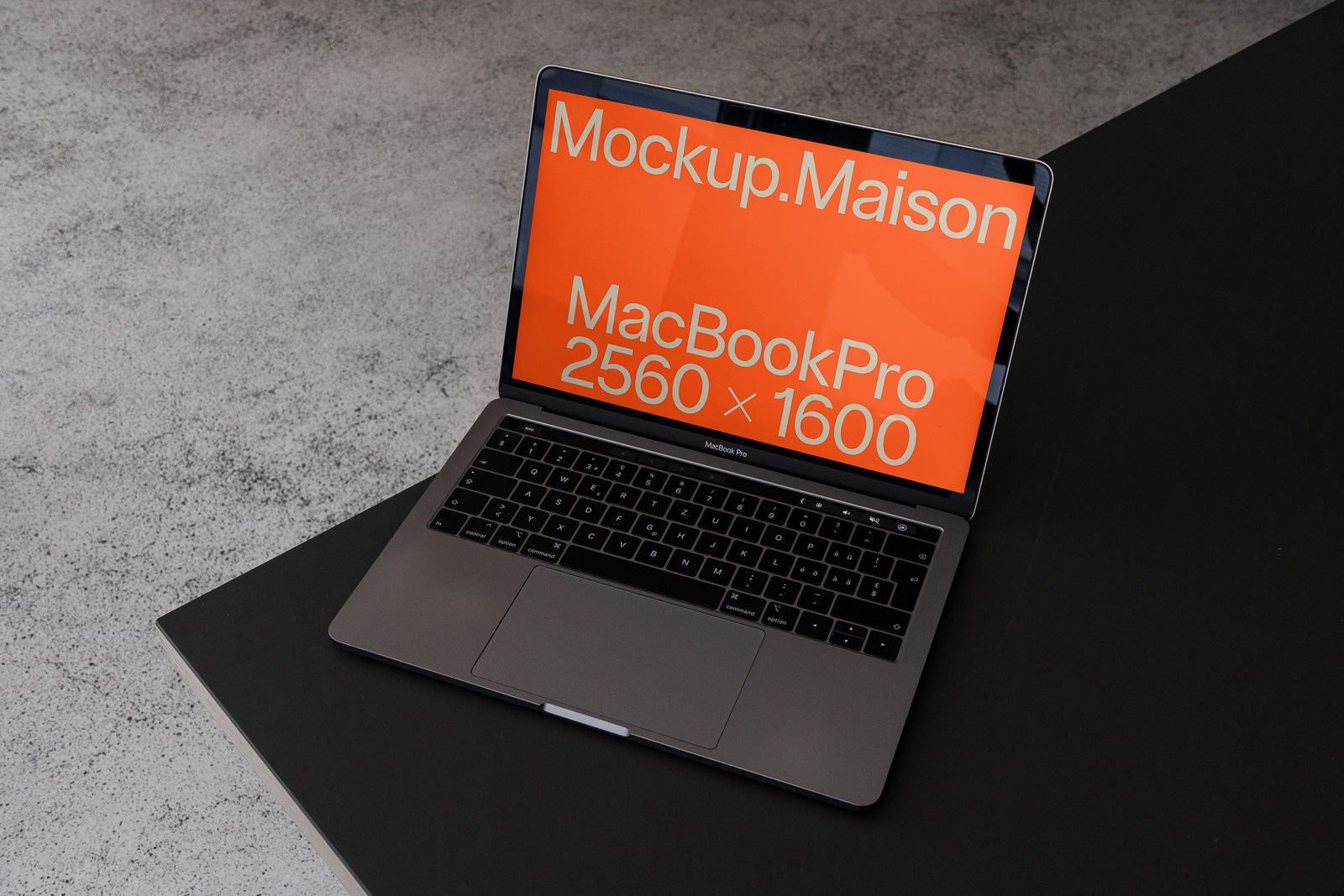 PSD mockup of a MacBook Pro on a dark table, displaying an orange screen with the text "Mockup.Maison" and "MacBookPro 2560 x 1600."