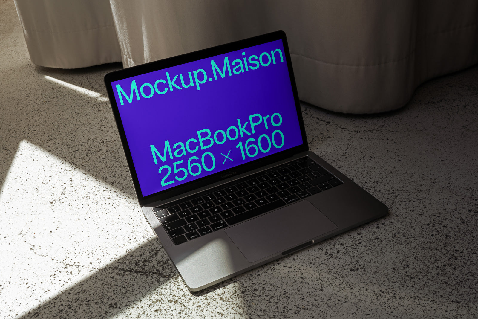 PSD mockup of a MacBook Pro on a textured surface with screen displaying "Mockup.Maison" and "MacBook Pro 2560 x 1600" in green text.