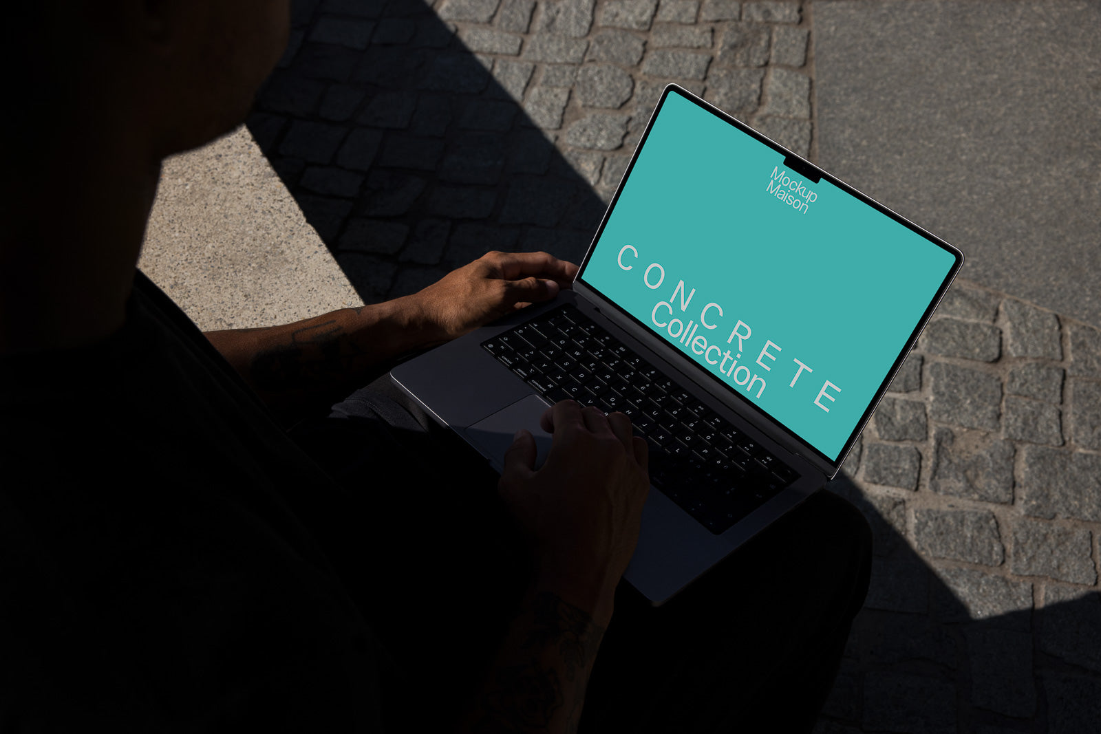 PSD mockup of a person using a laptop outdoors, displaying a "Concrete Collection" design with a turquoise background on the screen.