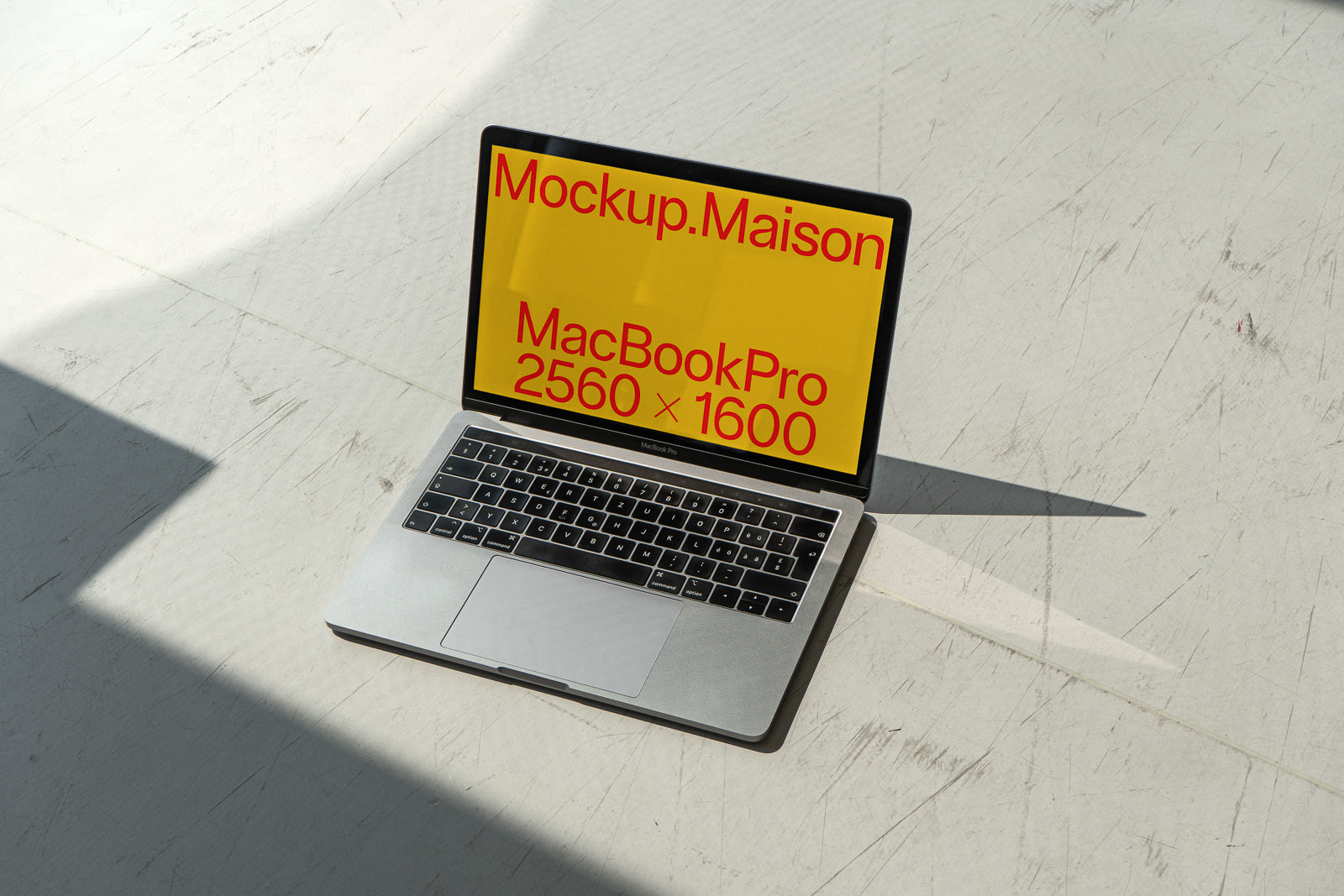 PSD mockup of a MacBook Pro on a textured surface, screen displaying "Mockup.Maison" with resolution 2560 x 1600.