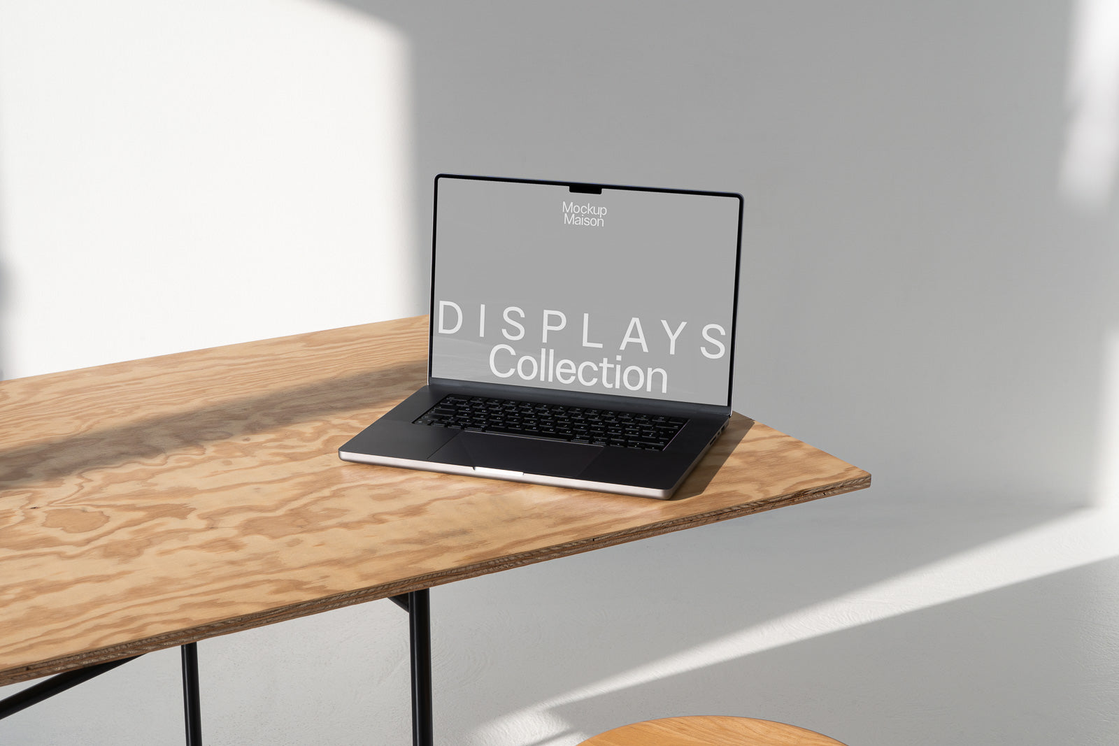 PSD mockup of a laptop on a wooden table with a shadow cast across the surface, featuring the text "DISPLAYS Collection" on the screen.