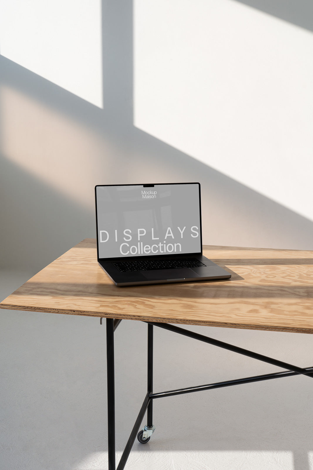 PSD mockup of a laptop on a wooden table with a shadowed wall background. The screen displays the words "Displays Collection."