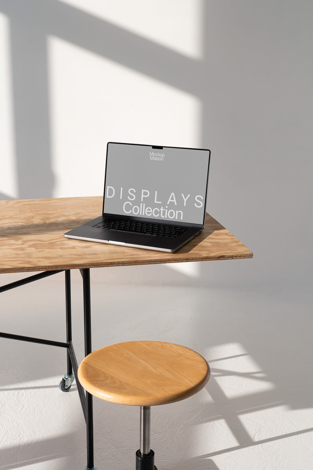 PSD mockup of a laptop on a wooden table with a wooden stool, showing a minimalist design with shadows, in a well-lit interior space.