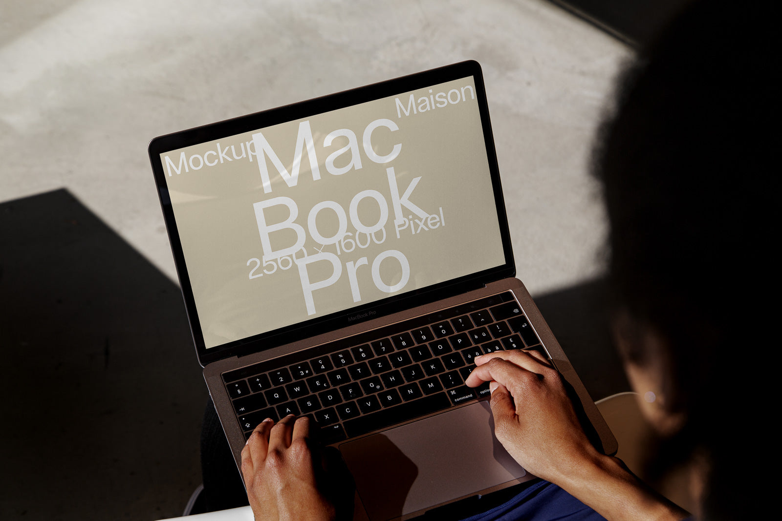 PSD mockup of a MacBook Pro with hands typing, displaying the screen text: "MacBook Pro 2560 x 1600 Pixel Mockup Maison," under natural lighting.