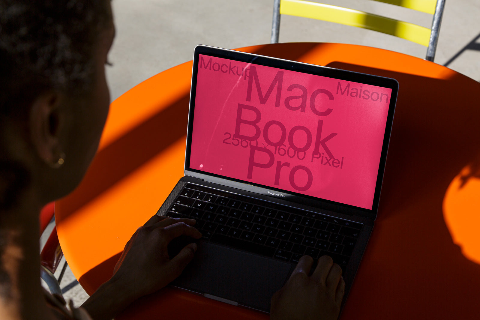 PSD mockup of a MacBook Pro on an orange table, screen displaying a red background with large text.