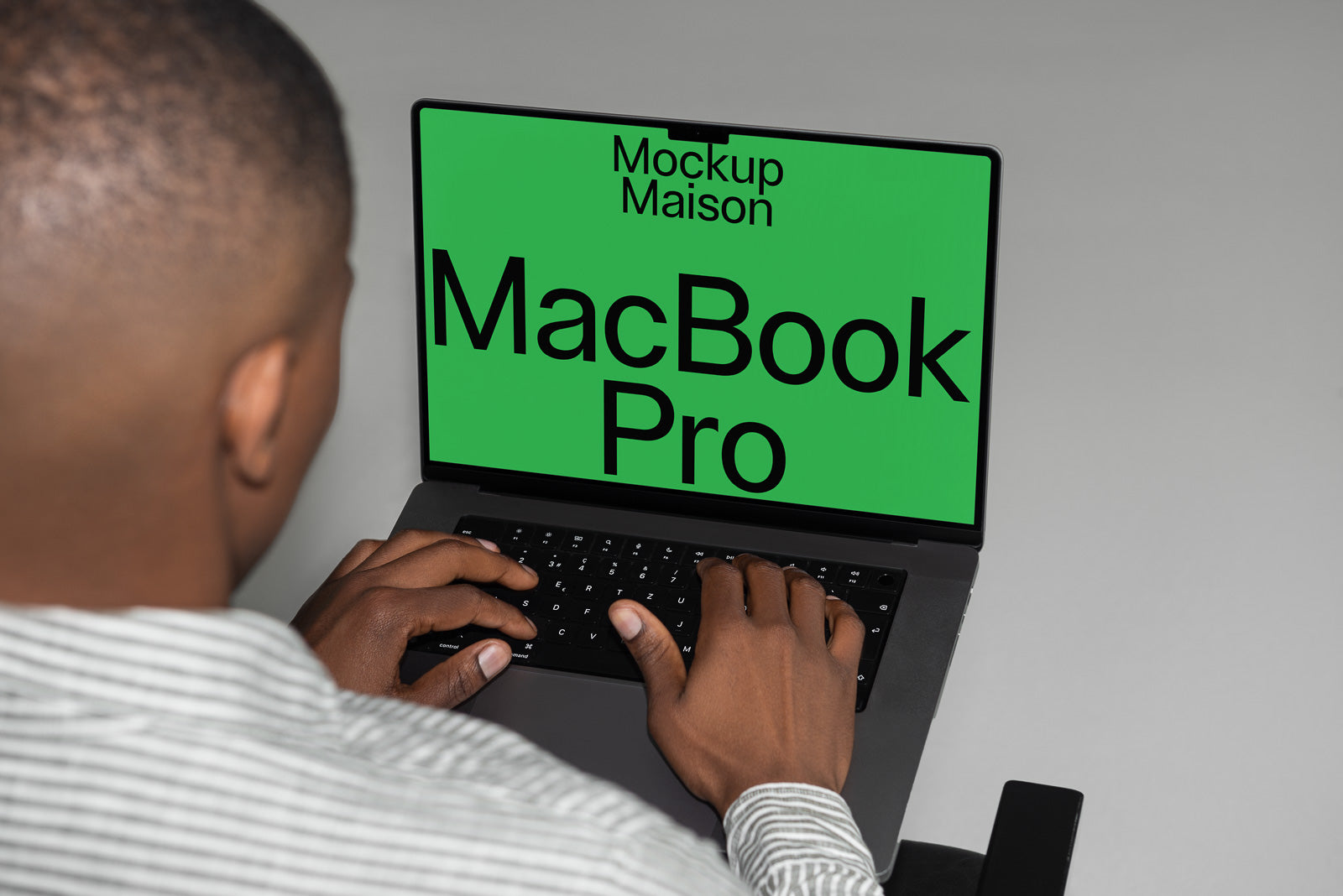 PSD mockup of a person using a MacBook Pro with a green screen displaying the text "Mockup Maison MacBook Pro."