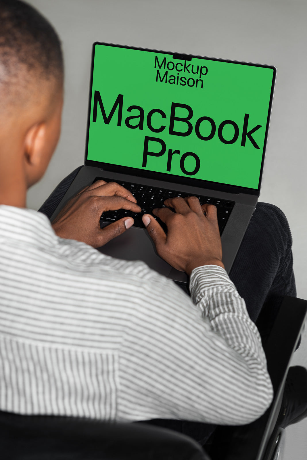 PSD mockup of a person typing on a laptop featuring a green screen displaying "MacBook Pro" and "Mockup Maison" in large black text.