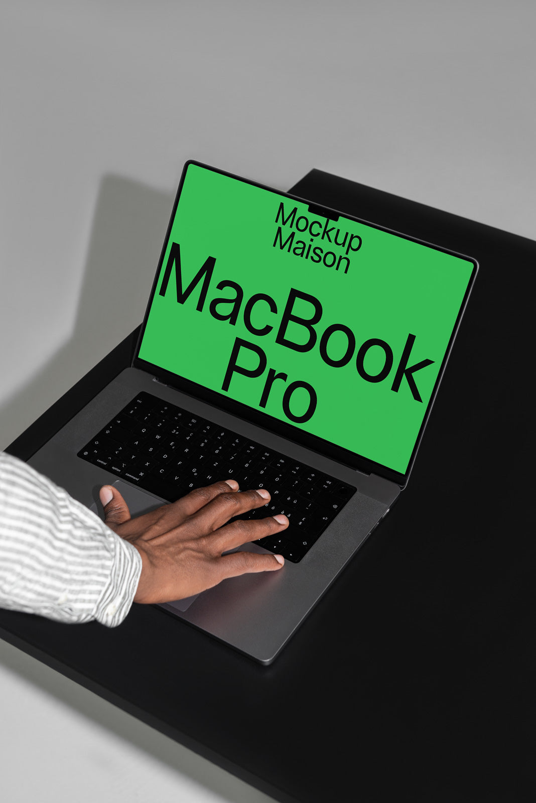 PSD mockup of a hand interacting with a MacBook Pro on a dark surface, screen showing "Mockup Maison" and "MacBook Pro" in bold text.