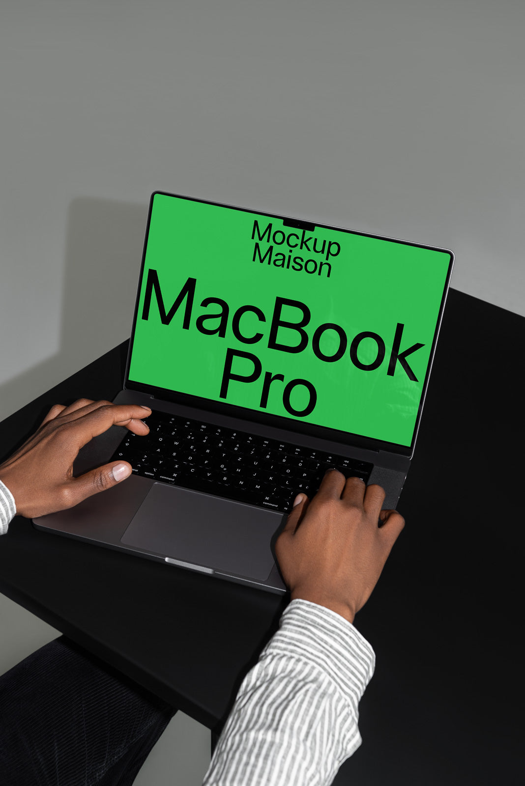 PSD mockup of a person typing on a MacBook Pro with a green screen displaying "Mockup Maison."
