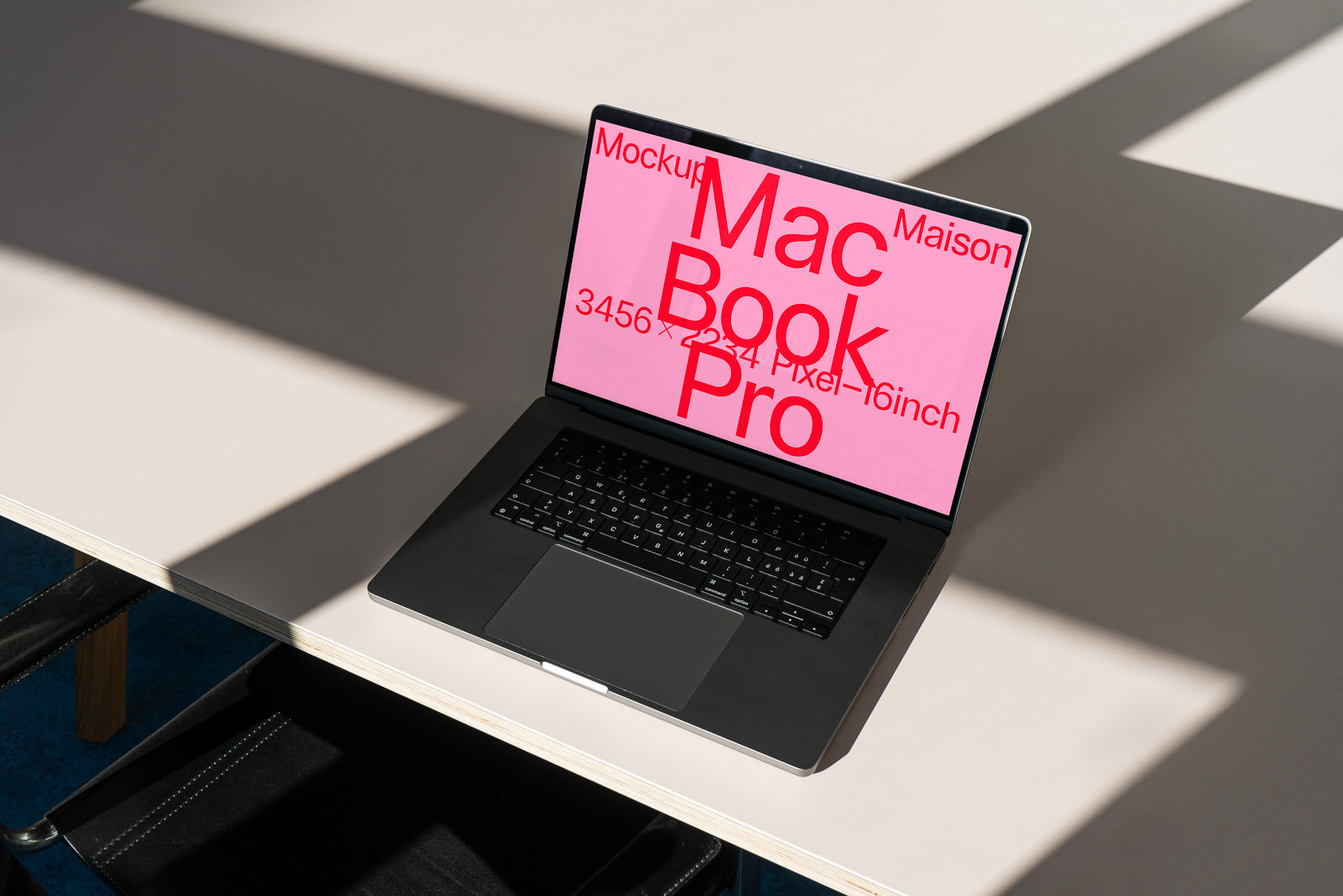 PSD mockup of a laptop with a pink screen displaying large red text on a minimalistic desk with shadows.