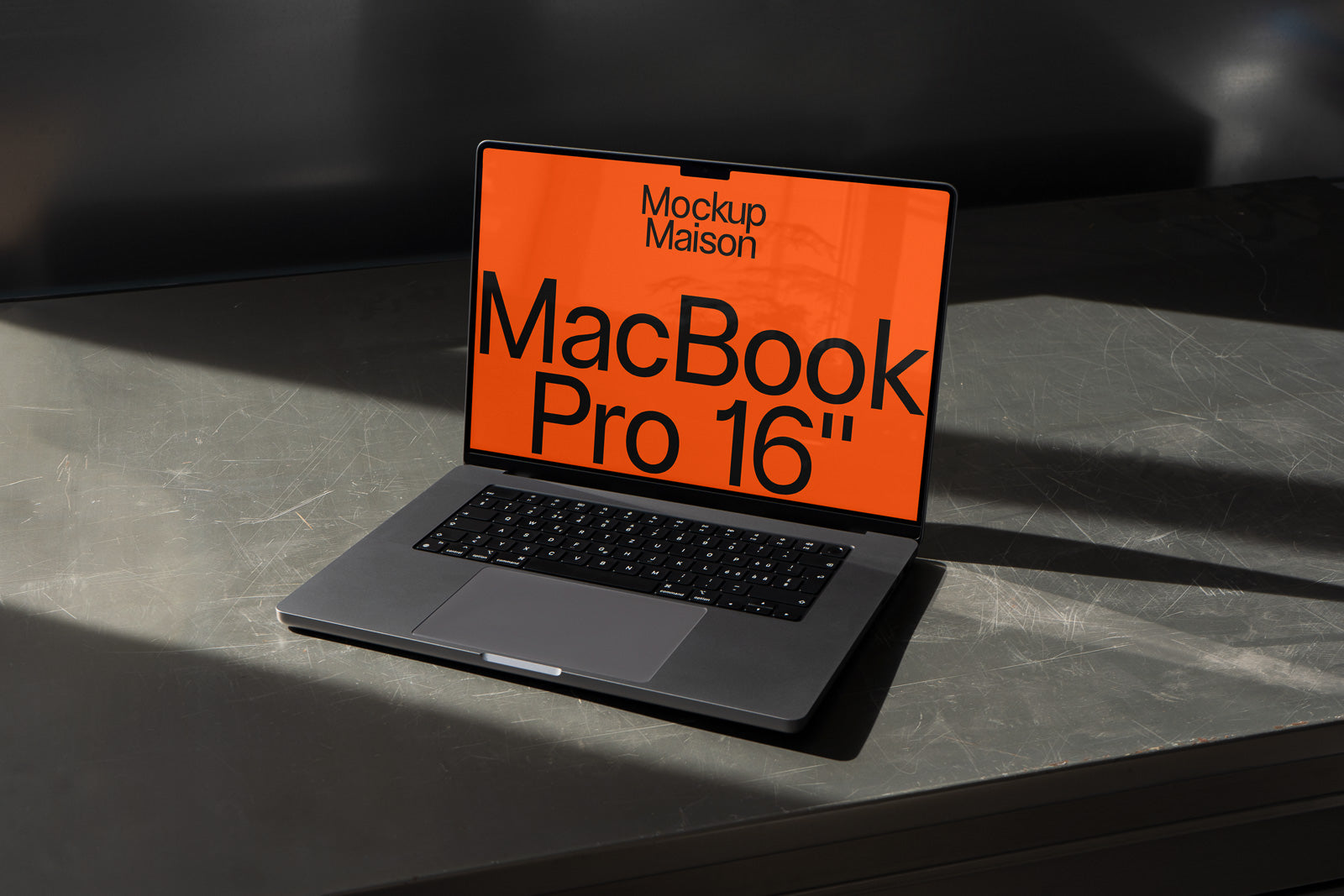 PSD mockup of a MacBook Pro 16" with an orange screen displaying bold text on a metal surface.