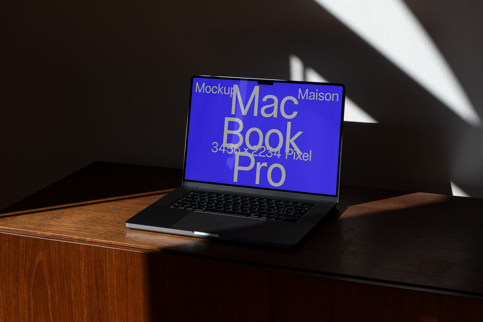 PSD mockup of a MacBook Pro displaying a blue screen with large white text, set on a wooden surface with dramatic light and shadow.