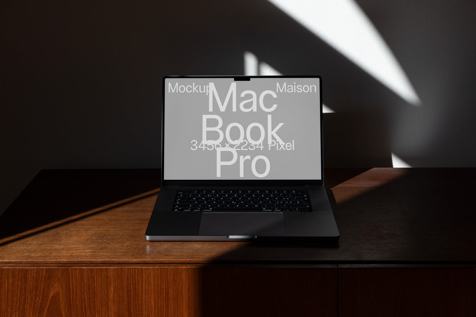 PSD mockup of a MacBook Pro on a wooden desk, positioned against a wall with dramatic lighting and shadows.