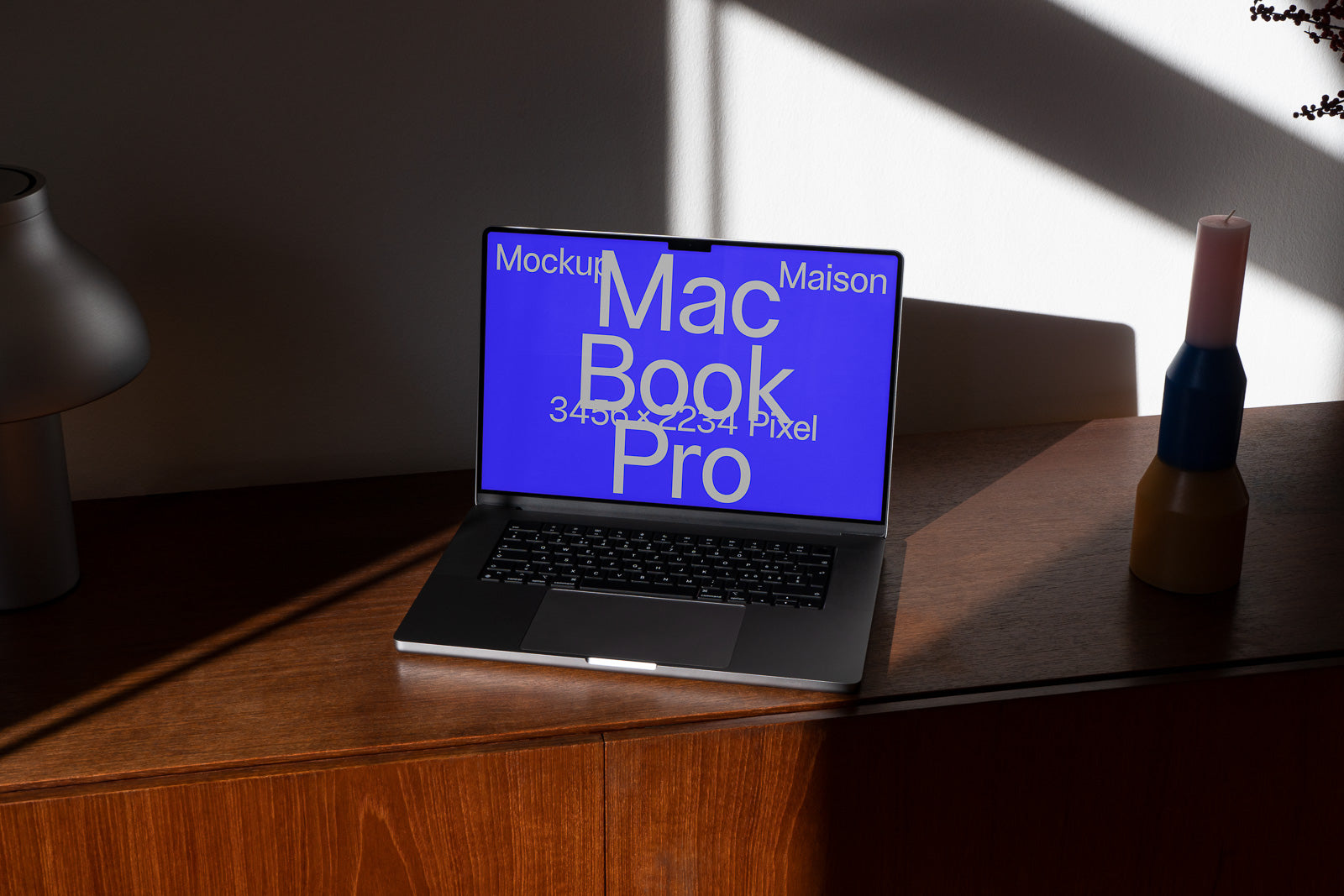 PSD mockup of an open MacBook Pro on a wooden table, displaying a blue screen with white text, beside a lamp and a candle.