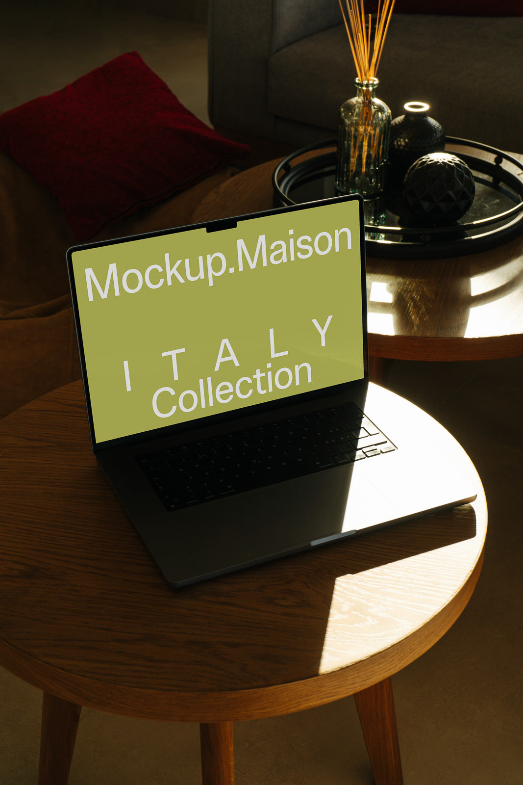 PSD mockup of a laptop on a wooden table in a warmly lit room, displaying "Mockup.Maison ITALY Collection" on its screen.