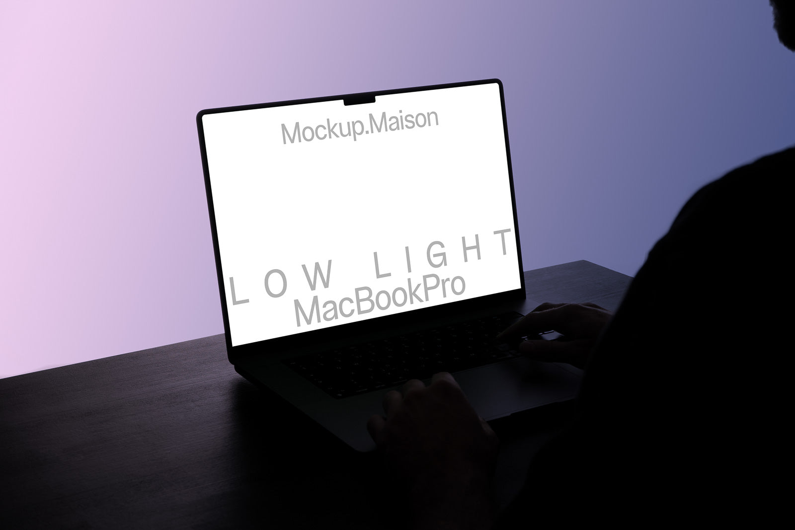 PSD mockup of an open MacBook Pro with a screen displaying the text "Mockup.Maison LOW LIGHT" in a dimly lit environment.
