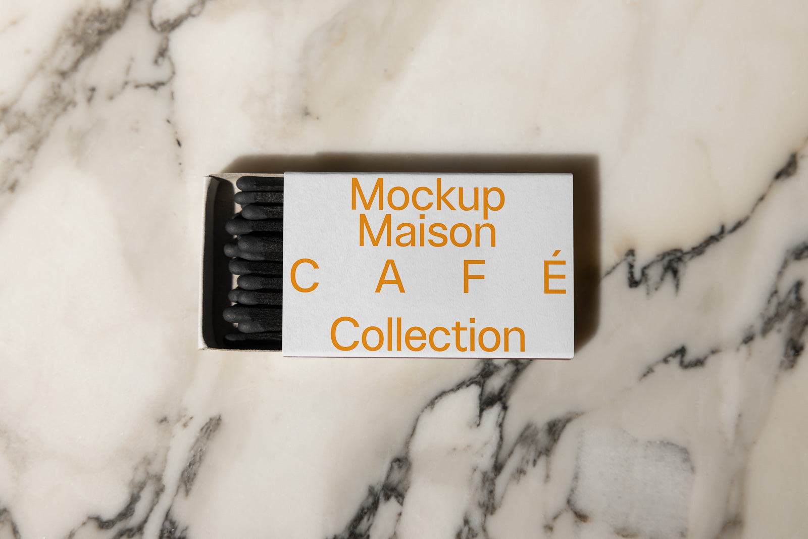 PSD mockup of a rectangular box of black cotton swabs on a marble surface, featuring "Mockup Maison Café Collection" text in orange.