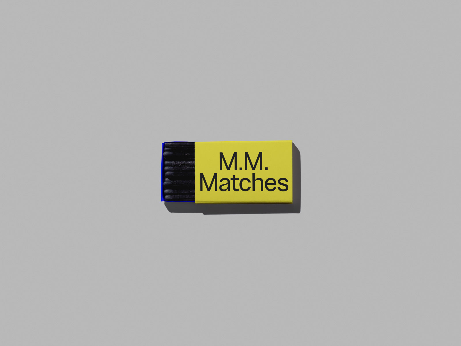 PSD mockup of a matchbox labeled "M.M. Matches" with a yellow cover and visible black matches inside.