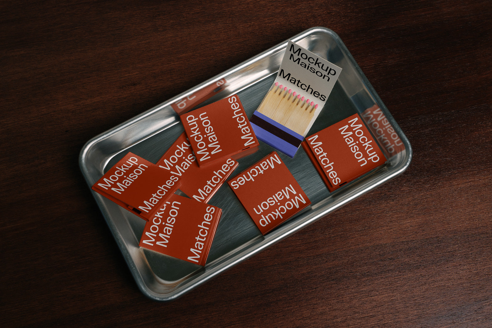 PSD mockup of red “Mockup Maison Matches” matchbooks arranged on a metal tray, displaying several open and closed match packs on a wooden table.