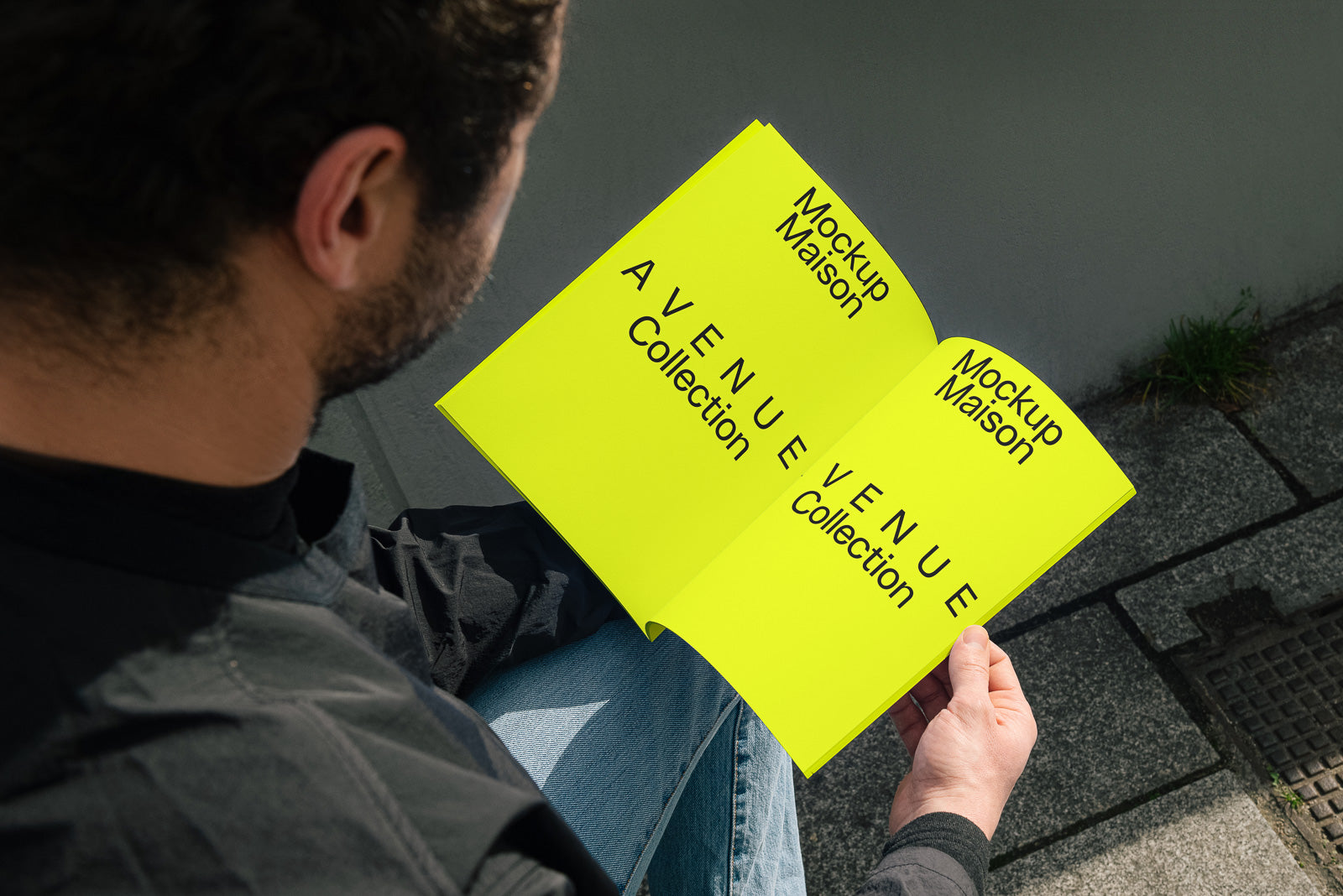 PSD mockup of a person holding an open book with bright yellow pages, displaying text "Mockup Maison Avenue Collection" in bold black font.