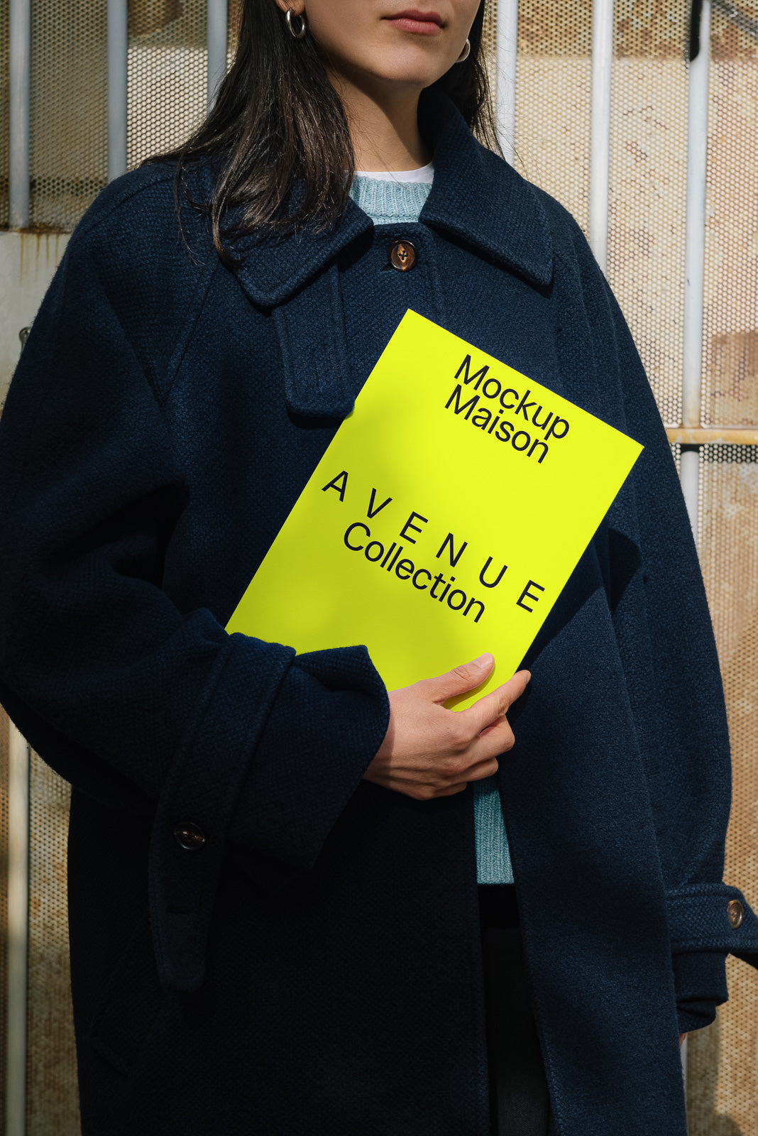 PSD mockup of a person holding a bright yellow booklet titled "Mockup Maison Avenue Collection" against a textured background.