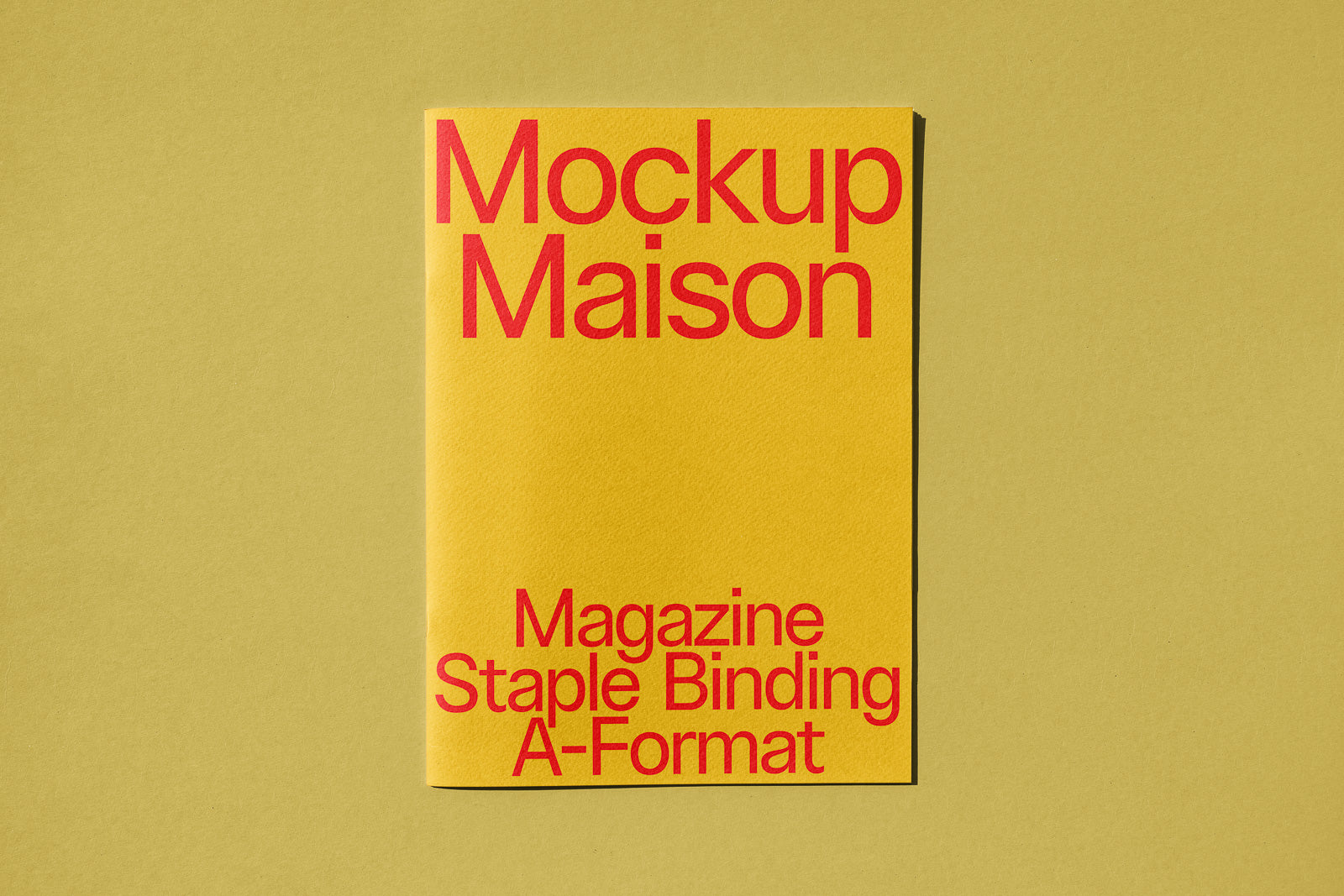 PSD mockup of a yellow magazine with red text, "Mockup Maison Magazine Staple Binding A-Format," on an olive background, showcasing typography.