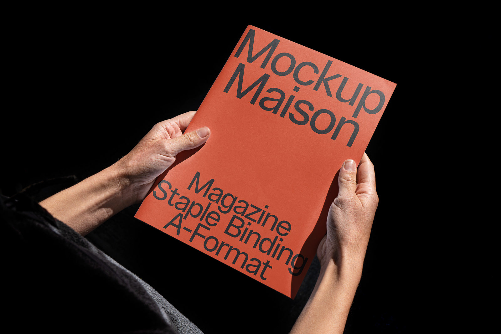 PSD mockup of a person holding a red magazine with "Mockup Maison" and "Magazine Staple Binding A-Format" text.