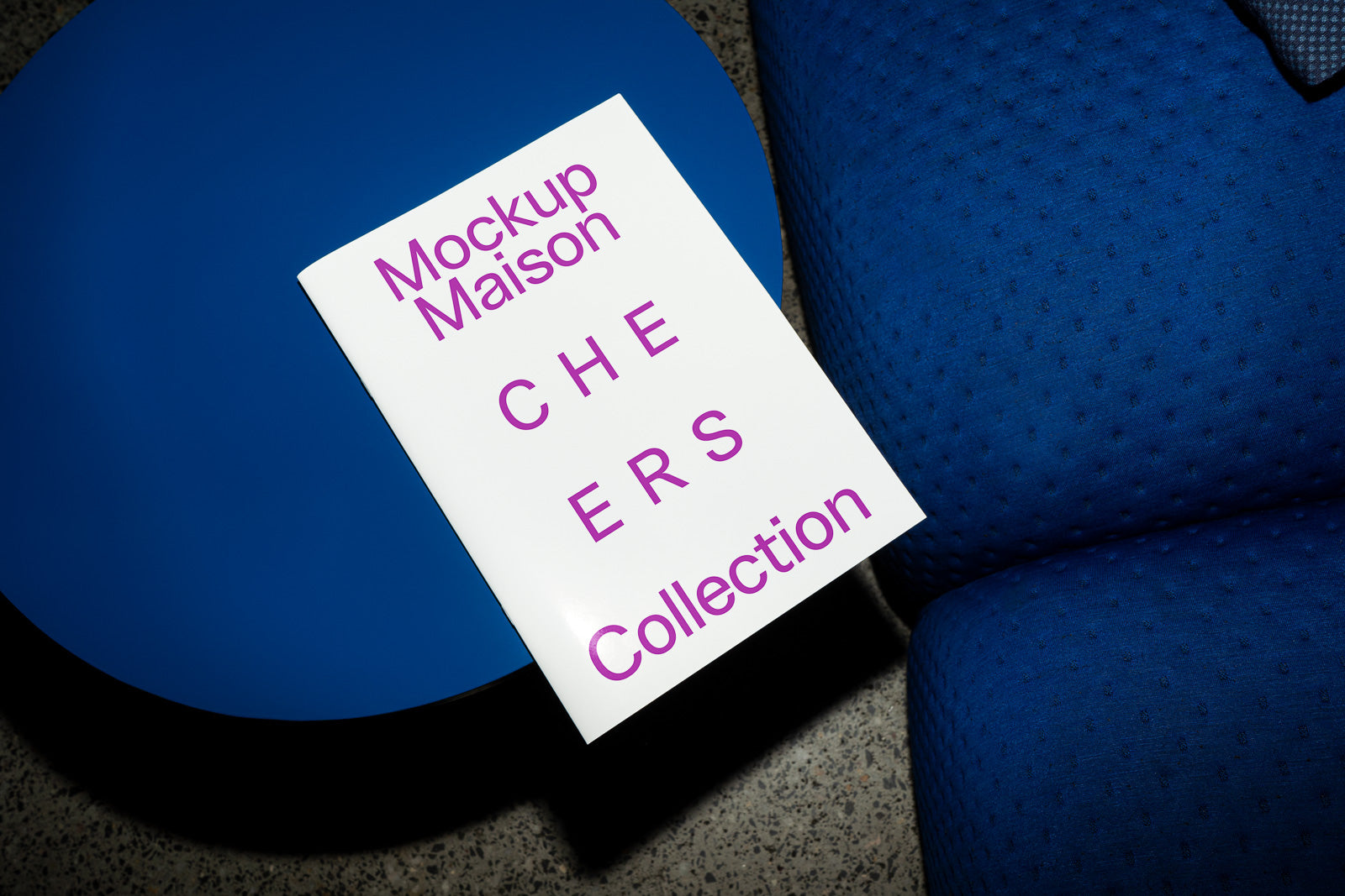 PSD mockup of a brochure titled "Mockup Maison Cheers Collection" resting on a vibrant blue surface.