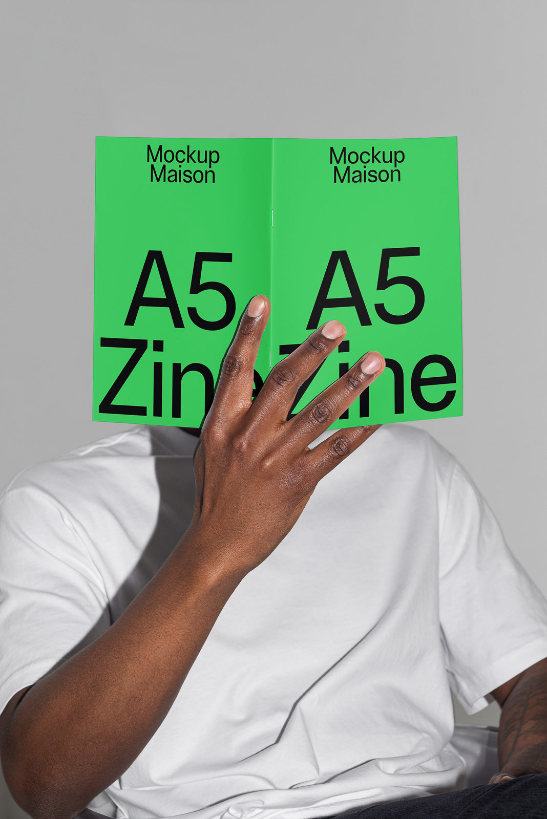 PSD mockup of an A5 zine held by a person wearing a white shirt, displaying cover with bold black text on a vibrant green background.