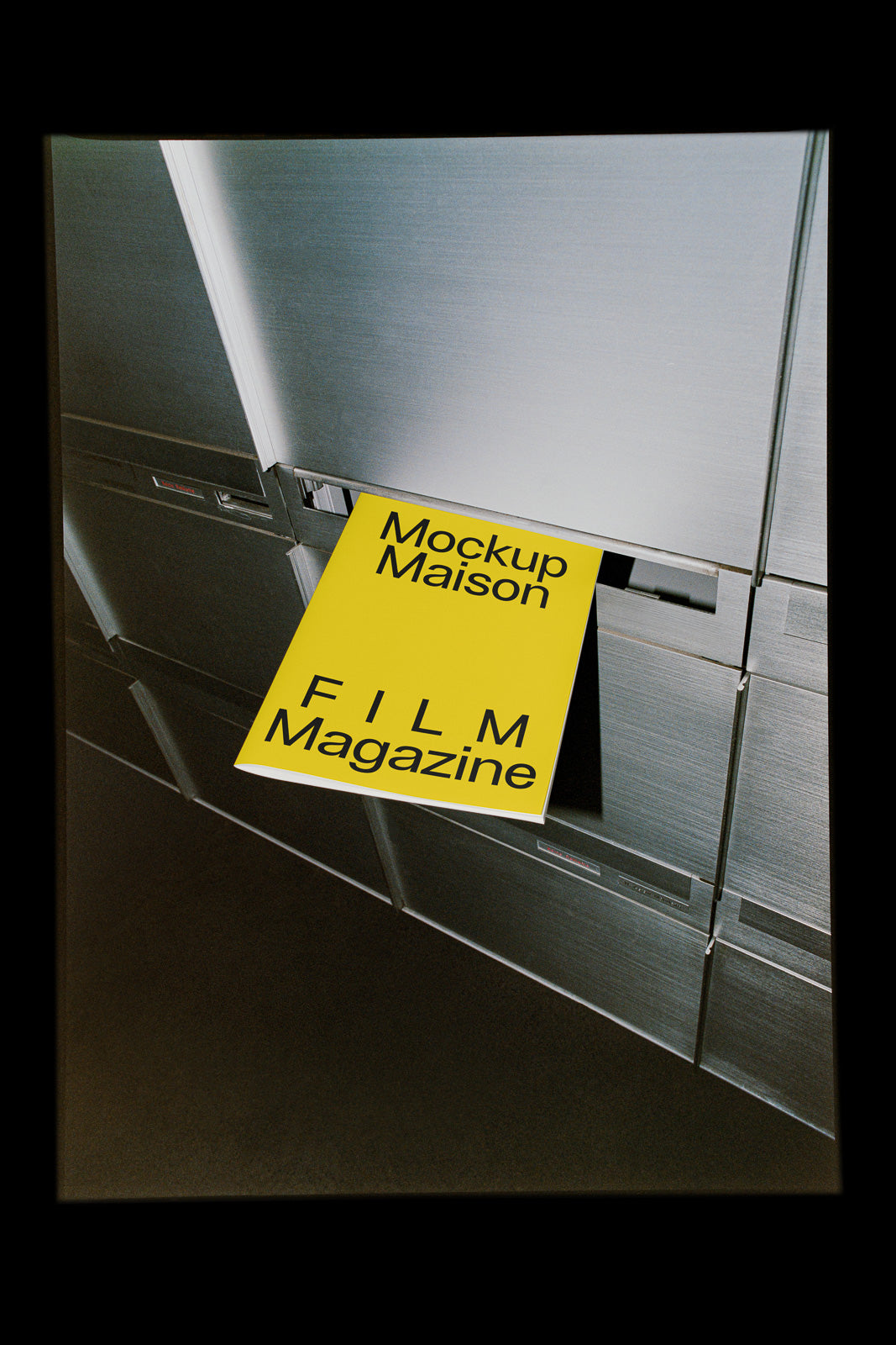PSD mockup of a yellow magazine with black text partially inserted into a metallic mailbox, titled "Mockup Maison FILM Magazine".
