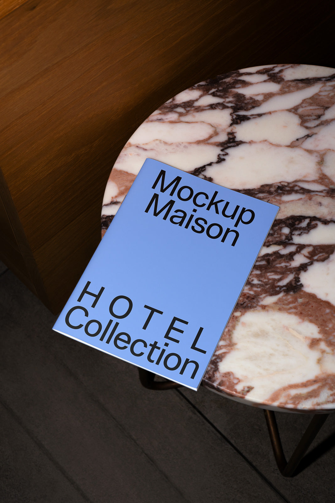 PSD mockup of a magazine cover titled "Mockup Maison HOTEL Collection" placed on a round marble-topped table next to a wooden surface.