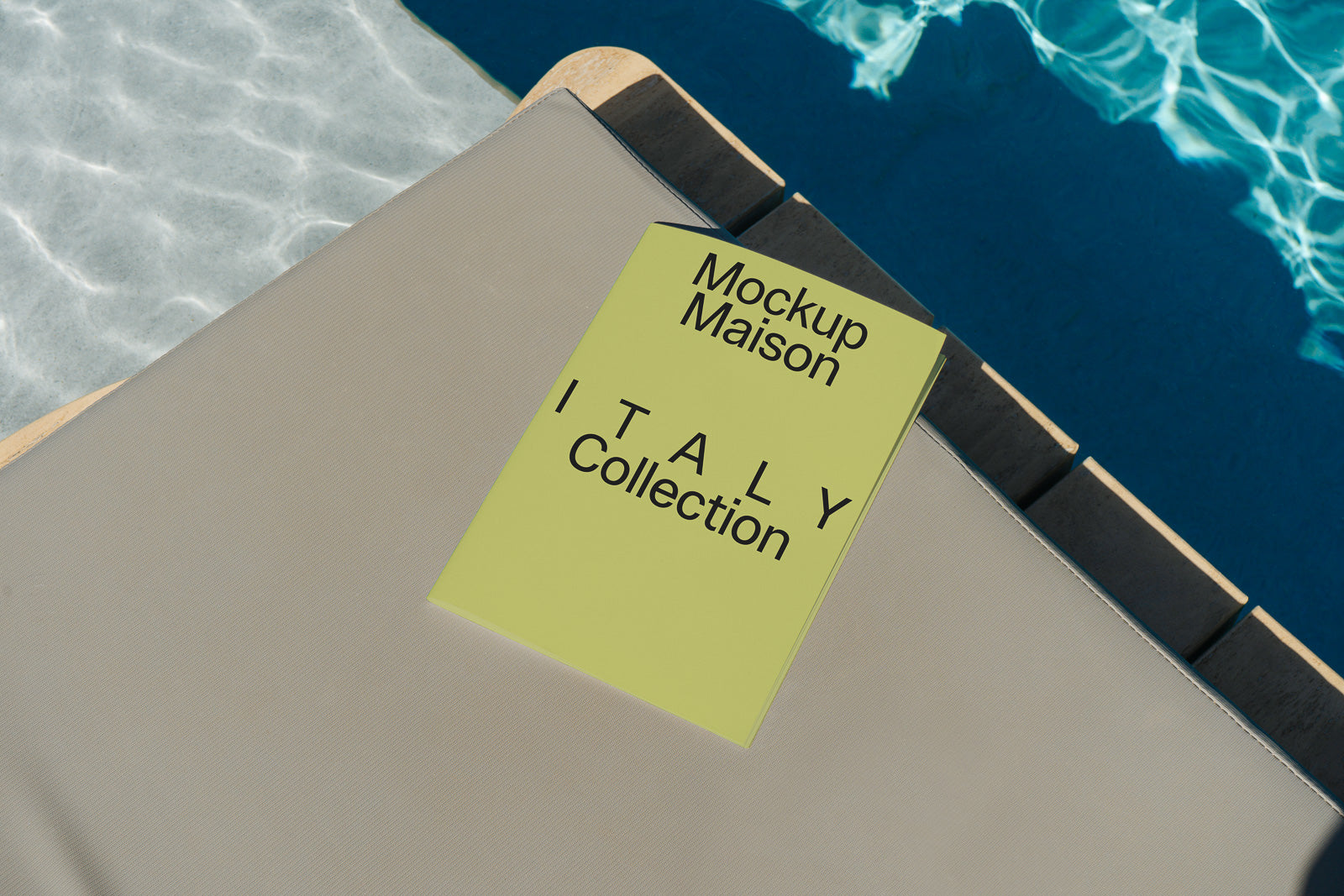 PSD mockup of a brochure titled "Mockup Maison ITALY Collection" placed on a lounge chair beside a swimming pool.