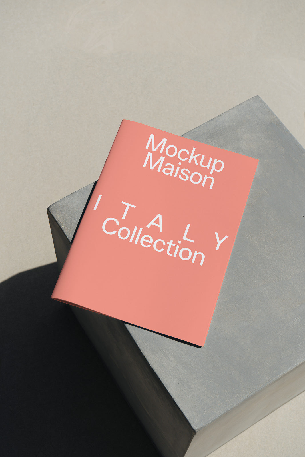 PSD mockup of a pink brochure titled "Mockup Maison ITALY Collection" resting on a gray surface, casting a shadow on the ground.