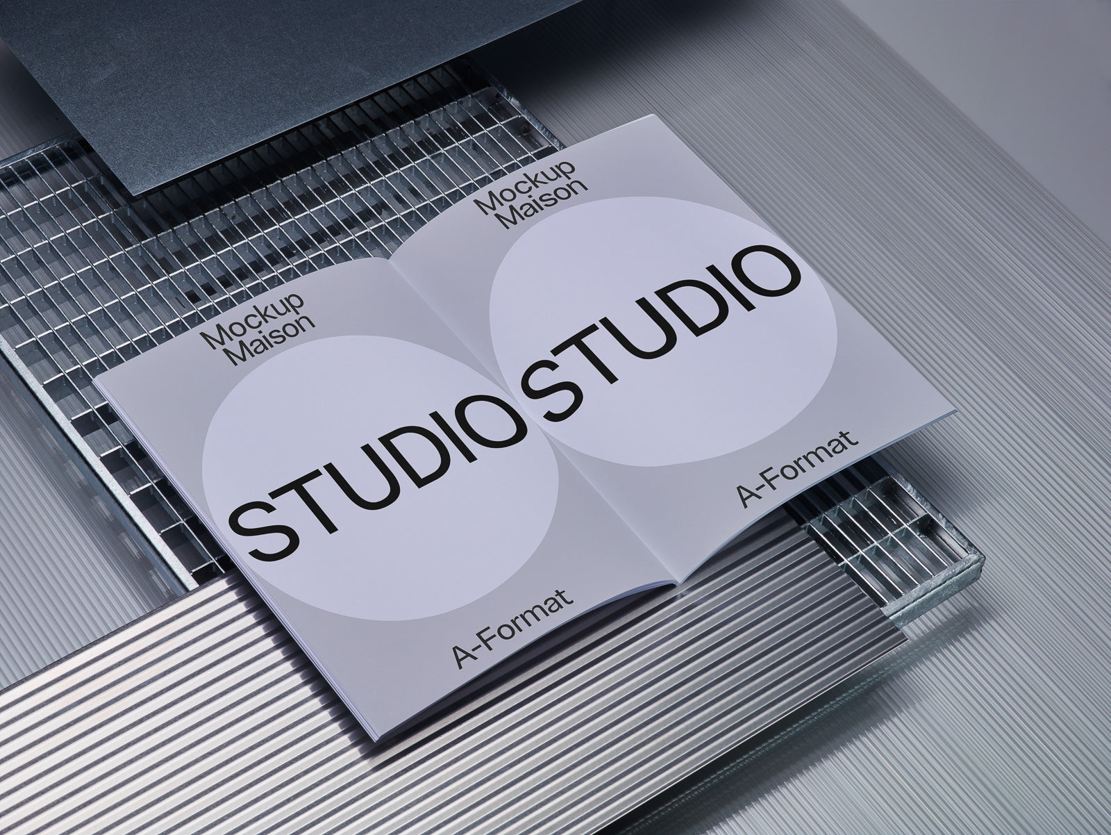 PSD mockup of open booklets on a textured metallic surface, featuring "Studio" and "A-Format" text, showcasing modern design and typography style.