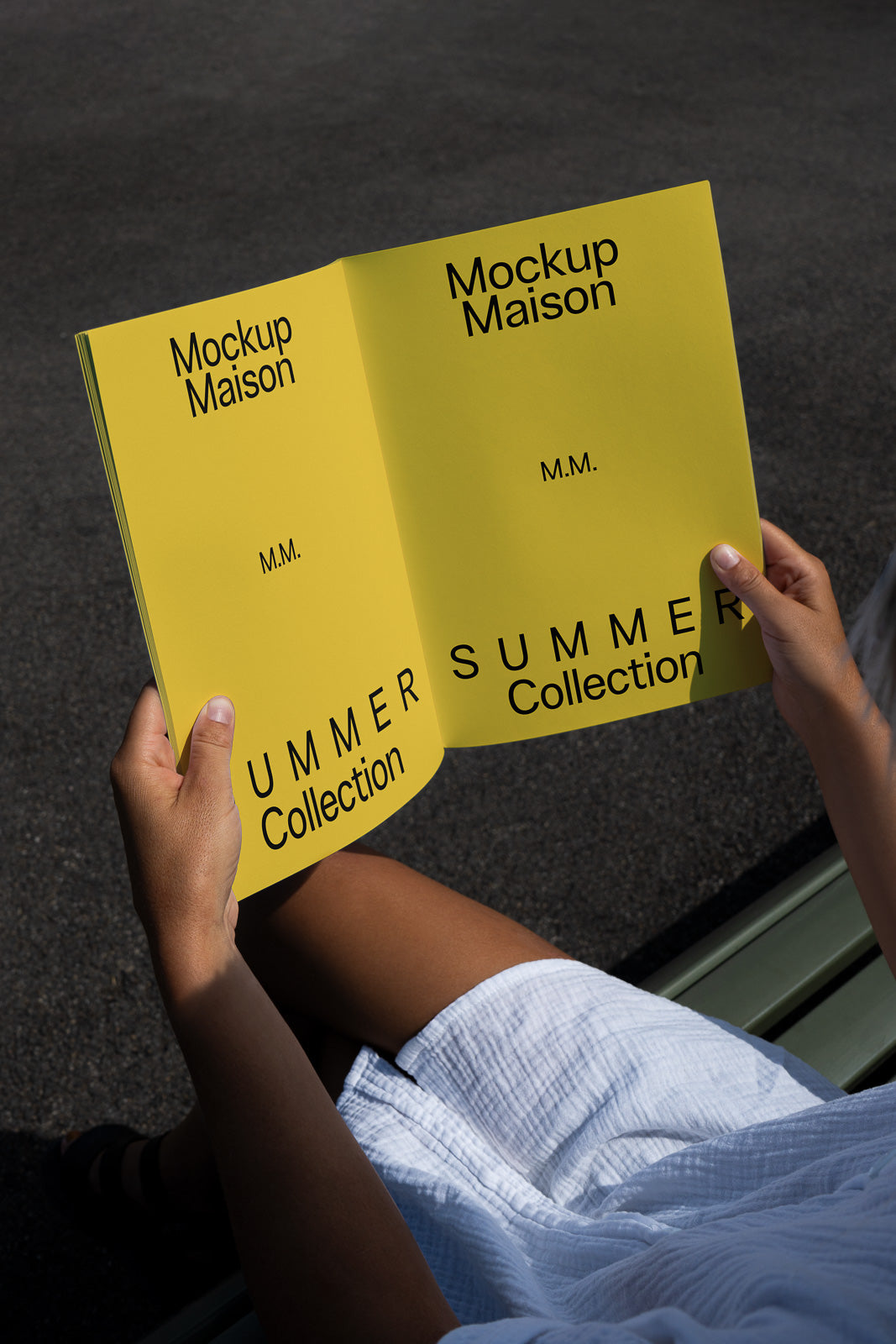 PSD mockup of a person holding a yellow booklet titled "Mockup Maison," featuring the text "Summer Collection" and "M.M." on both pages.