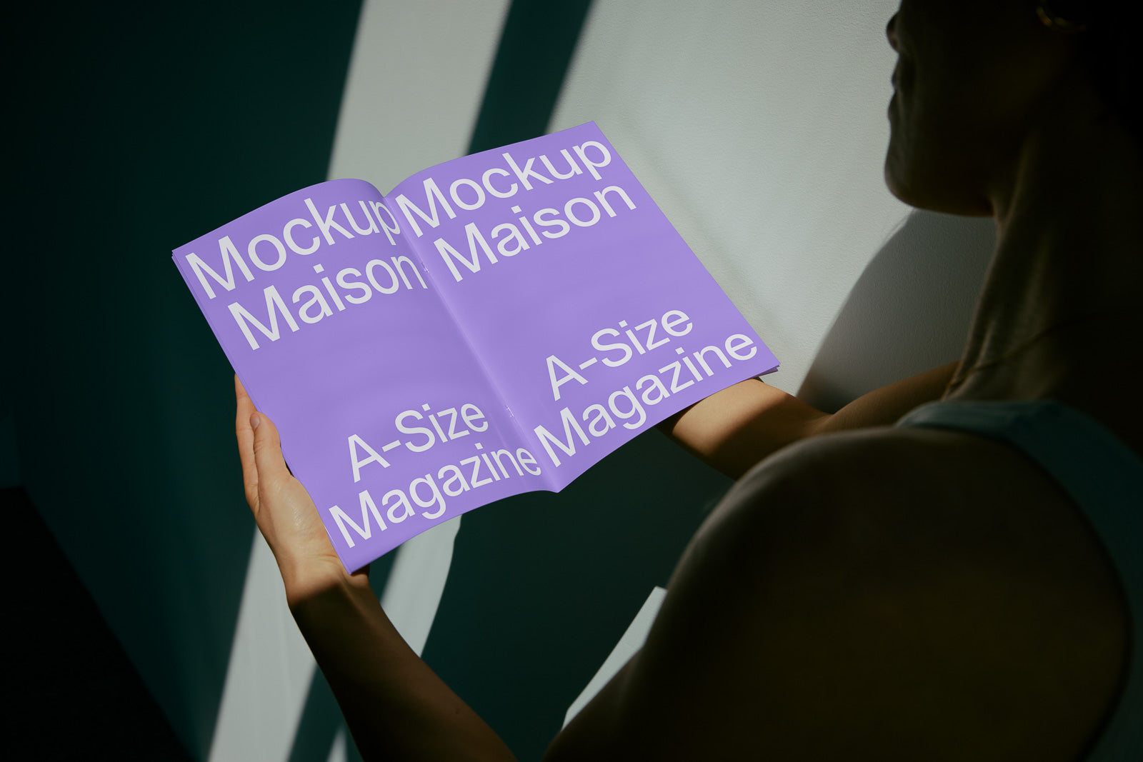 PSD mockup of a person holding an open A-size magazine with a purple cover, featuring the text “Mockup Maison” and “A-Size Magazine” in large white letters.