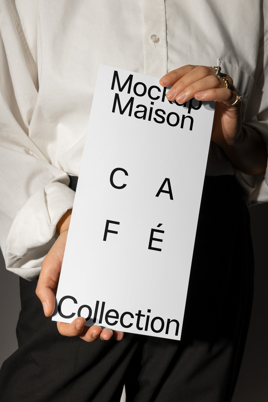 PSD mockup of a person holding a vertical card with text "Mockup Maison" and "Café Collection" in a minimal design.