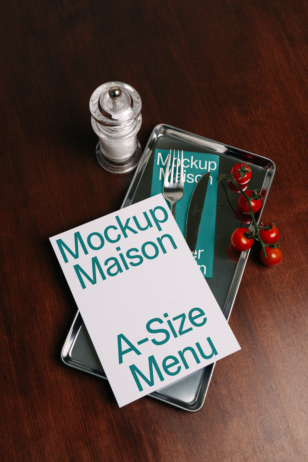 PSD mockup of a restaurant menu on a metal tray with fork, knife, cherry tomatoes, and salt shaker on a wooden table.
